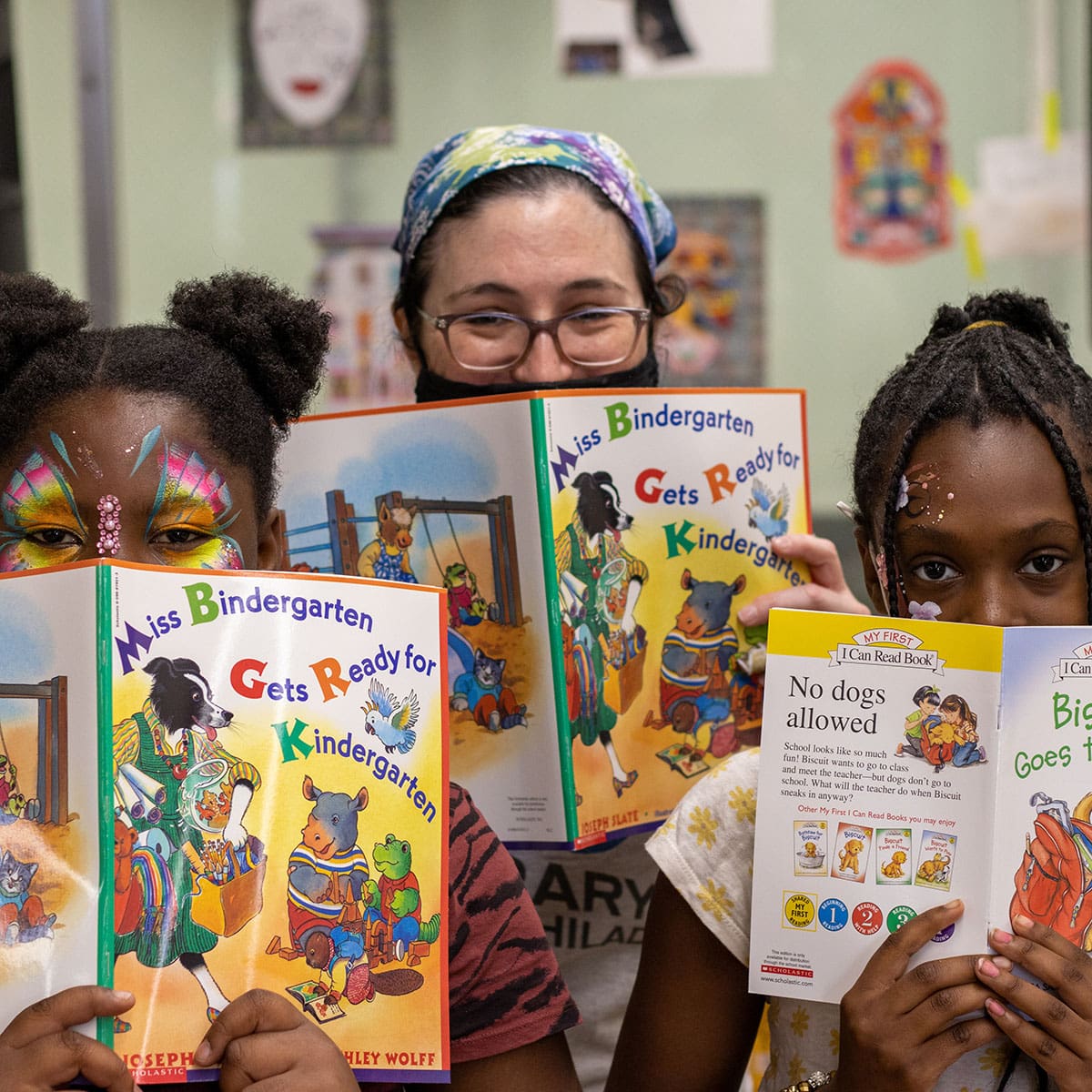 Three people looking forward with open books covering their mouths.