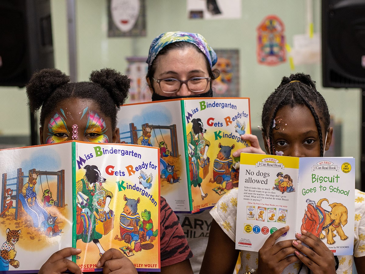 Three people looking forward with open books covering their mouths.